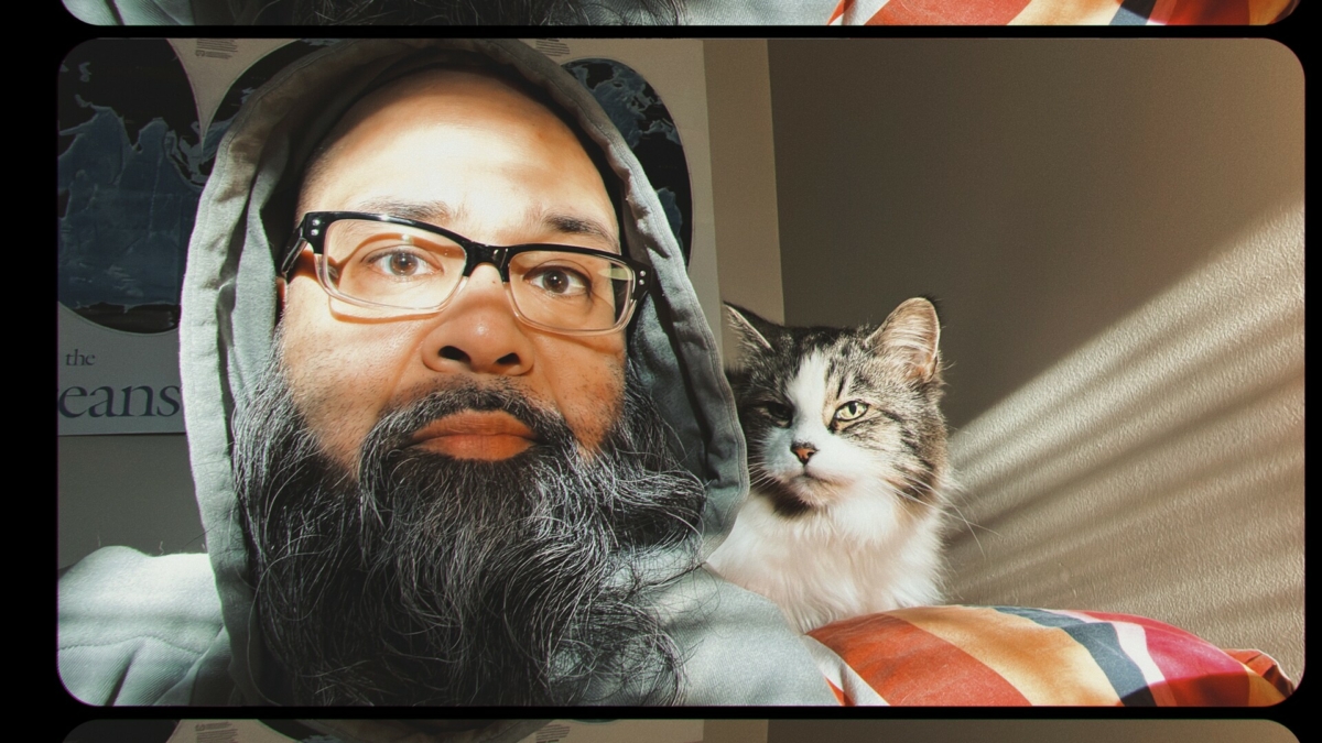 gandalf looking indian dude with a medium haired calico cat, sunlight streaming on their faces. also i don’t know what ‘calico’ is but it sounds right.